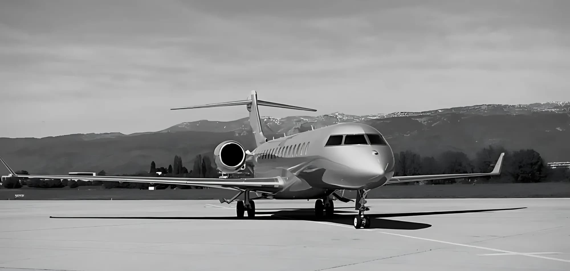 A sleek private jet parked on the tarmac with mountains in the background